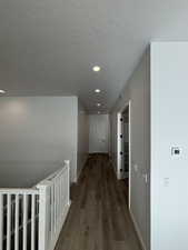 Hallway with a textured ceiling and dark hardwood / wood-style flooring