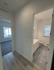 Bathroom featuring hardwood / wood-style flooring, vanity, toilet, and a wealth of natural light