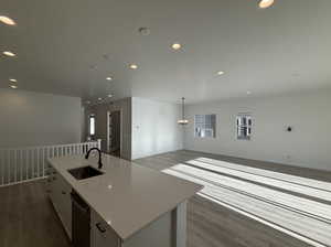 Kitchen with white cabinets, dark hardwood / wood-style flooring, an island with sink, and sink