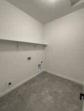 Laundry area with hookup for an electric dryer, hookup for a washing machine, and dark tile patterned floors