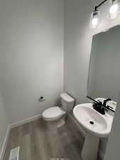 Bathroom with hardwood / wood-style flooring, toilet, and sink