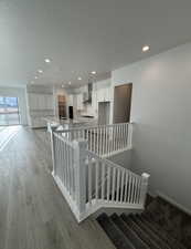 Stairway featuring a textured ceiling, wood-type flooring, and sink