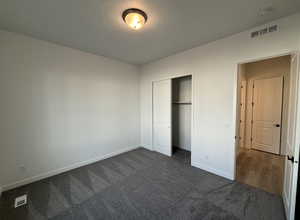 Unfurnished bedroom with dark colored carpet and a closet