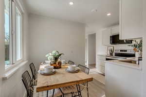 Kitchen featuring ornamental molding, white cabinets, light hardwood / wood-style floors, and appliances with stainless steel finishes