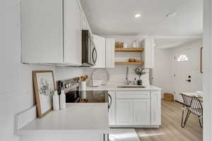 Kitchen featuring stainless steel appliances, white cabinetry, sink, and light hardwood / wood-style floors