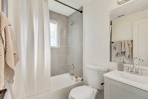 Full bathroom with shower / tub combo with curtain, vanity, and toilet