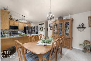 Dining area featuring light colored carpet, lofted ceiling, and a notable chandelier