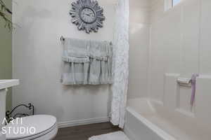 Bathroom featuring hardwood / wood-style flooring, toilet, and shower / tub combo