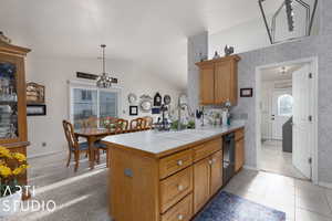 Kitchen with lofted ceiling, sink, black dishwasher, a notable chandelier, and light colored carpet