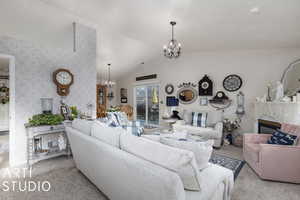 Living room featuring a premium fireplace, lofted ceiling, light carpet, and an inviting chandelier