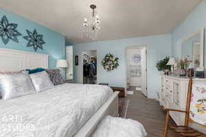 Bedroom with an inviting chandelier, dark hardwood / wood-style floors, a spacious closet, connected bathroom, and a closet