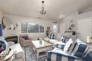 Carpeted living room with lofted ceiling and an inviting chandelier