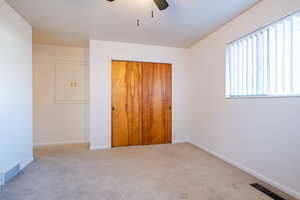 Unfurnished bedroom with ceiling fan, light carpet, and a closet