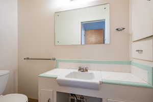 Bathroom featuring tasteful backsplash, toilet, and sink