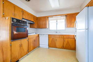 Kitchen featuring white appliances, sink, and range hood