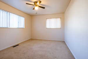 Spare room with ceiling fan, a healthy amount of sunlight, and light colored carpet