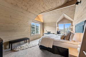 Carpeted bedroom featuring wooden walls, wooden ceiling, multiple windows, and lofted ceiling