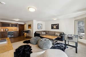 Living room with hardwood / wood-style flooring, beverage cooler, and indoor bar