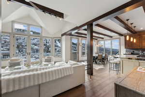 Living room featuring a chandelier, light wood-type flooring, high vaulted ceiling, and plenty of natural light