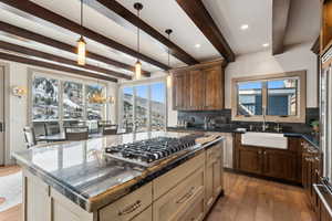 Kitchen featuring dark stone counters, beamed ceiling, a kitchen island, and stainless steel appliances