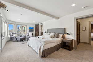 Bedroom featuring light carpet, a barn door, and beamed ceiling