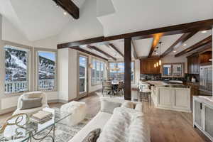 Living room with beamed ceiling, high vaulted ceiling, light hardwood / wood-style flooring, and sink