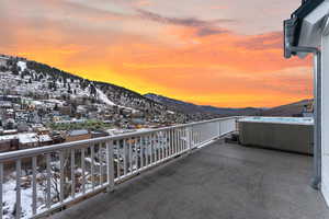 Snow covered back of property with a mountain view and a hot tub