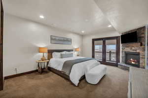 Bedroom featuring a textured ceiling, light colored carpet, and a fireplace