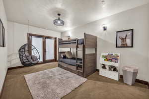 Carpeted bedroom with french doors and a textured ceiling