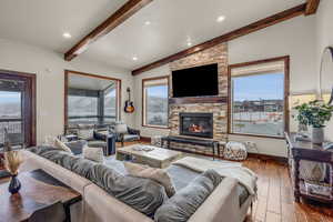 Living room featuring a fireplace, plenty of natural light, hardwood / wood-style floors, and vaulted ceiling with beams