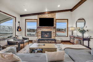 Living room with vaulted ceiling with beams, plenty of natural light, light hardwood / wood-style floors, and a fireplace