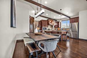 Dining space with vaulted ceiling with beams, sink, and dark wood-type flooring