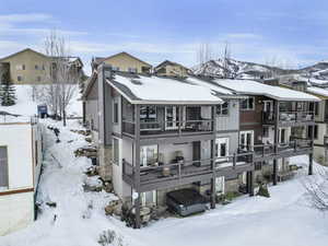 Snow covered rear of property featuring a mountain view and a balcony