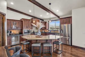 Kitchen featuring tasteful backsplash, stainless steel appliances, beverage cooler, beam ceiling, and hanging light fixtures