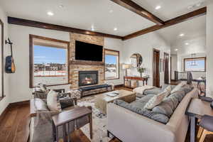 Living room featuring wood-type flooring, a stone fireplace, and a wealth of natural light