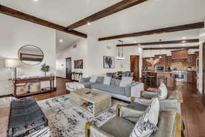 Living room featuring beam ceiling, dark hardwood / wood-style flooring, and high vaulted ceiling