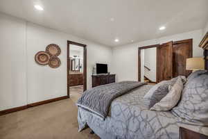 Bedroom featuring light carpet and ensuite bath