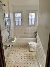 Bathroom featuring toilet, a tub, and sink