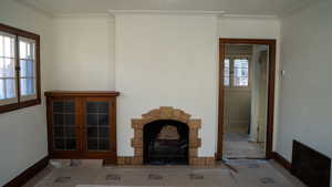 Living room featuring a healthy amount of sunlight, crown molding, and french doors on custom built in cabinetry