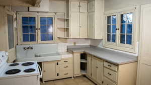 Kitchen featuring light tile patterned flooring, electric stove, and cream cabinets