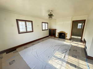 Living room featuring ceiling fan, crown molding, and a fireplace