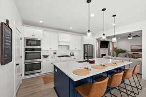 Kitchen with stainless steel appliances, a kitchen island with sink, sink, pendant lighting, and light hardwood / wood-style floors