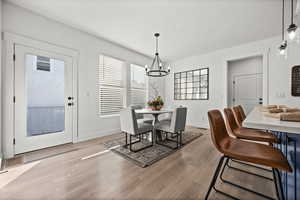 Dining space with a textured ceiling, a notable chandelier, and light wood-type flooring