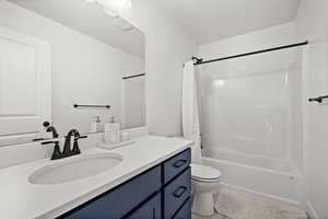 Full bathroom featuring toilet, a textured ceiling, vanity, and shower / tub combo with curtain