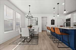 Dining room featuring sink, light hardwood / wood-style flooring, a textured ceiling, and an inviting chandelier