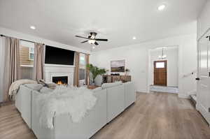 Living room featuring a healthy amount of sunlight, ceiling fan with notable chandelier, and light wood-type flooring