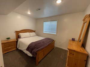 Bedroom with dark carpet and a textured ceiling