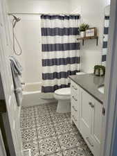 Full bathroom featuring toilet, vanity, and shower / tub combo with curtain