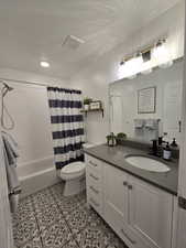 Full bathroom with shower / bath combination with curtain, toilet, a textured ceiling, and vanity