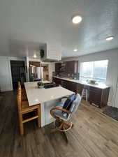 Kitchen featuring dark brown cabinetry, a textured ceiling, appliances with stainless steel finishes, and LVP flooring